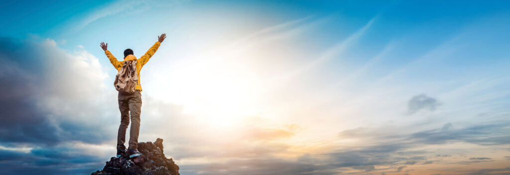 Man on mountain with bright sky
