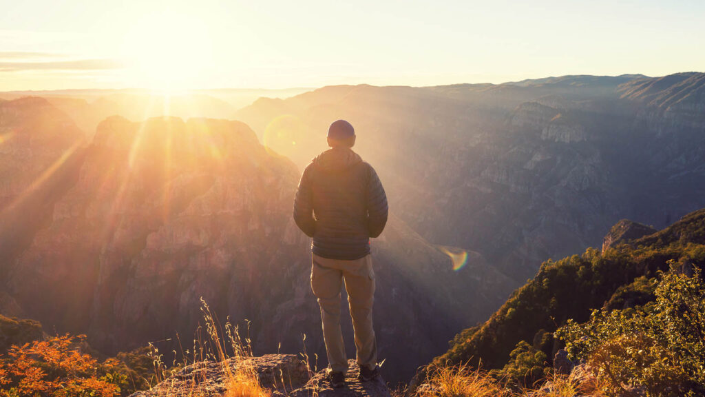 A solitary man standing in soft natural light in nature at sunrise